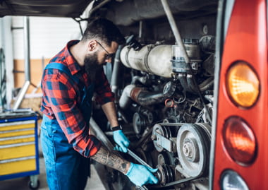 a man performs maintenance on the back of a charter bus